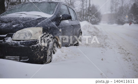 Car stuck in deep snow on a frozen road during winter blizzard, challenging driving 140411611