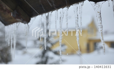 Icicle formation hanging from roof eave in a cold snowy winter landscape Icicle formation hanging from roof eave in a cold snowy winter landscape 140411631