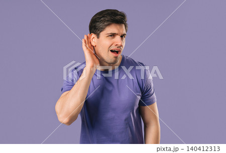 Young Man Pointing To Ear With Confused Face, Signaling He Cant Hear Clearly Young Man Pointing To Ear With Confused Face, Signaling He Cant Hear Clearly 140412313
