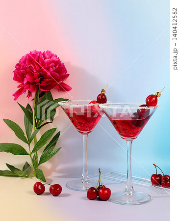 Modern still life with a summer alcoholic cocktail and peony flowers against a sunny background. Cherry martini on the rocks for a party. Minimalistic concept for a bar or cafe. Advertising banner Modern still life with a summer alcoholic cocktail and peony flowers against a sunny background. Cherry martini on the rocks for a party. Minimalistic concept for a bar or cafe. Advertising banner 140412582