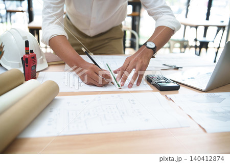 Architect or Engineer Working on Building Plans with Tools on Desk Architect or Engineer Working on Building Plans with Tools on Desk 140412874