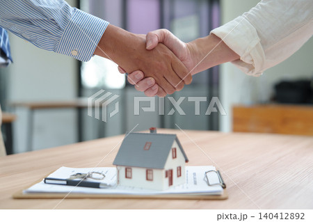Business Handshake Over Home Purchase Agreement in Real Estate Transaction Business Handshake Over Home Purchase Agreement in Real Estate Transaction 140412892