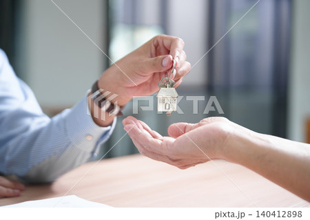 Key handover in real estate transaction symbolizing home ownership and investment 140412898