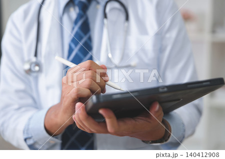Doctor in Clinic Using Tablet for Patient Records Doctor in Clinic Using Tablet for Patient Records 140412908