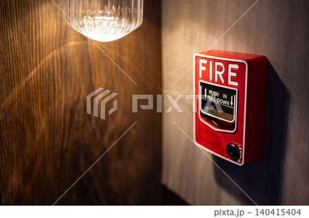 Red fire alarm switch mounted on wooden wall in public building 140415404