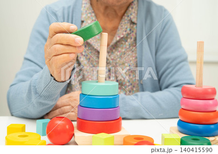 Asian elderly woman playing enhancing skill board game. Asian elderly woman playing enhancing skill board game. 140415590