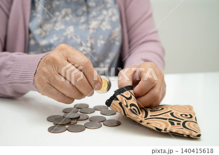 Asian senior or elderly old lady woman holding counting coin money in bag. Poverty, saving problem in retirement. Asian senior or elderly old lady woman holding counting coin money in bag. Poverty, saving problem in retirement. 140415618