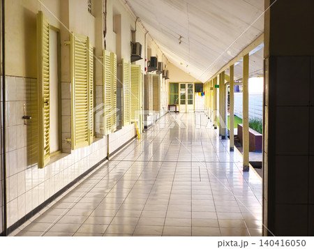 Empty interior hallway of a public building or hospital clinic featuring classic yellow louvered windows and tiled flooring Empty interior hallway of a public building or hospital clinic featuring classic yellow louvered windows and tiled flooring 140416050