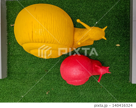 whimsical outdoor art installation featuring two large, textured fiberglass snail statues  140416324
