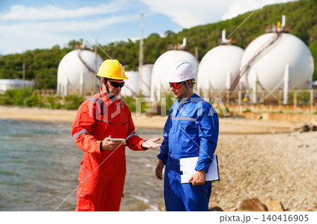 Industrial engineers discussing data at oil refinery plant Industrial engineers discussing data at oil refinery plant 140416905