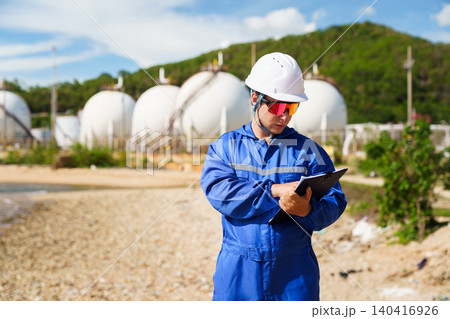 Caucasian engineer inspecting valves at an oil refinery plant Caucasian engineer inspecting valves at an oil refinery plant 140416926