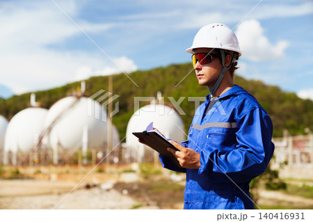 Caucasian engineer inspecting valves at an oil refinery plant Caucasian engineer inspecting valves at an oil refinery plant 140416931