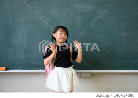 教室の黒板の前でランドセルを背負い両手を広げて笑顔を見せる小学1年生の女の子 教室の黒板の前でランドセルを背負い両手を広げて笑顔を見せる小学1年生の女の子 140417086
