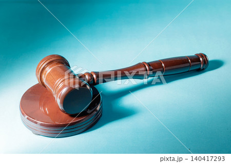 A classic brown wooden justice gavel resting on its sounding block against a vibrant teal blue background, symbolizing law, order, court trials, and authority. High Quality Photo A classic brown wooden justice gavel resting on its sounding block against a vibrant teal blue background, symbolizing law, order, court trials, and authority. High Quality Photo 140417293
