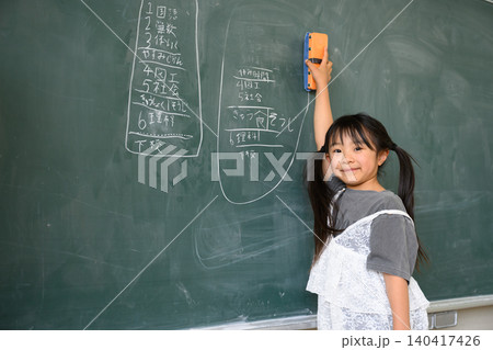 教室で笑顔で黒板を消す低学年の女子小学生 教室で笑顔で黒板を消す低学年の女子小学生 140417426
