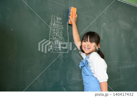 教室で笑顔で黒板を消す低学年の女子小学生 教室で笑顔で黒板を消す低学年の女子小学生 140417432