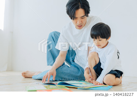 父親と一緒に絵本を読む男の子 140418227