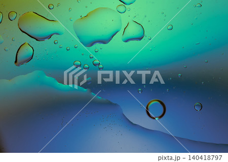 Macro shot of fluid dynamics showing floating oil drops over vibrant, colorful light leaks Macro shot of fluid dynamics showing floating oil drops over vibrant, colorful light leaks 140418797