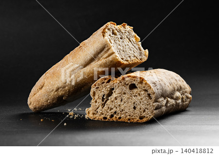 Close-up of freshly baked sourdough bread loaf broken into two pieces on dark surface Close-up of freshly baked sourdough bread loaf broken into two pieces on dark surface 140418812