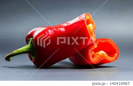 Studio slice shot of a crisp red sweet pepper sliced in half, showing internal hollow cavity and glossy skin Studio slice shot of a crisp red sweet pepper sliced in half, showing internal hollow cavity and glossy skin 140418967