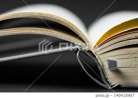 Low angle macro shot of an open book spine and pages on a dark background 140418987