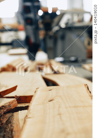 Workers prepare wooden planks at a furniture workshop with tools in the background Workers prepare wooden planks at a furniture workshop with tools in the background 140419010
