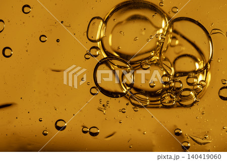 Macro shot of textured amber liquid with floating oil droplets and swirling dark ink patterns Macro shot of textured amber liquid with floating oil droplets and swirling dark ink patterns 140419060
