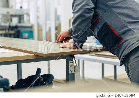 Craftsman measures wood in furniture workshop for building project during daytime work hours 140419094