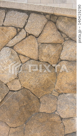 Vertical natural stone wall texture with irregular shapes and warm earthy tones Vertical natural stone wall texture with irregular shapes and warm earthy tones 140419290