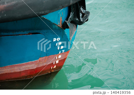 White draft marks on a blue and red ship hull reflecting in green harbor water 140419356