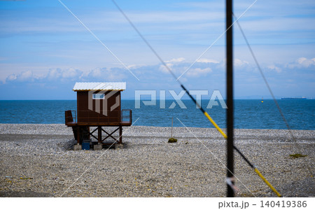 Minimalist view of a wooden lifeguard hut on a stone beach under a clear blue sky Minimalist view of a wooden lifeguard hut on a stone beach under a clear blue sky 140419386
