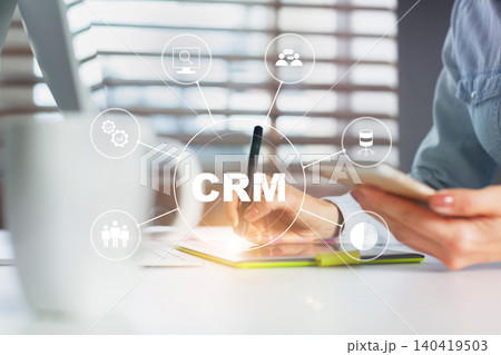 Digital interaction with CRM tools by a person at an office desk in the afternoon hours Digital interaction with CRM tools by a person at an office desk in the afternoon hours 140419503