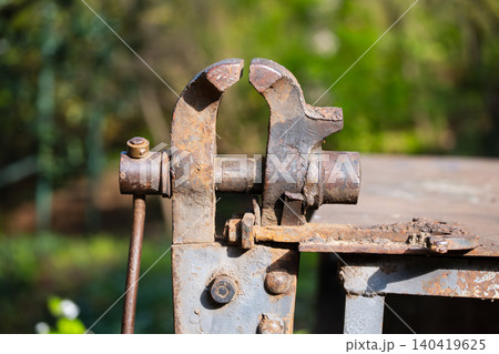 Heavy-duty vintage iron vice with rust texture positioned against a blurred green background Heavy-duty vintage iron vice with rust texture positioned against a blurred green background 140419625