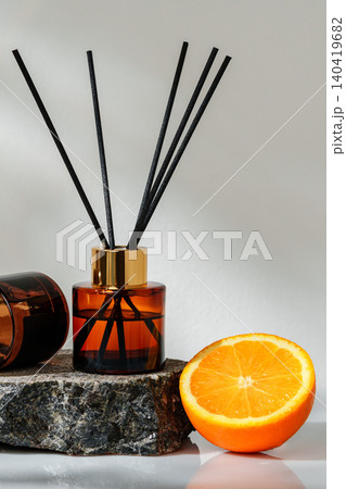 Scent diffuser beside orange on stone surface in bright light 140419682