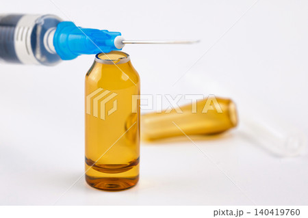 Close-up of a hypodermic needle being positioned over an open glass vial for extraction 140419760