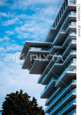 High-angle view of a contemporary glass building with unique cantilevered balconies against a blue sky 140419821
