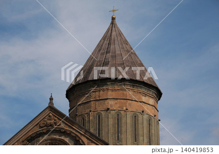 Low angle view of a conical stone dome and arched facade against a bright blue sky Low angle view of a conical stone dome and arched facade against a bright blue sky 140419853