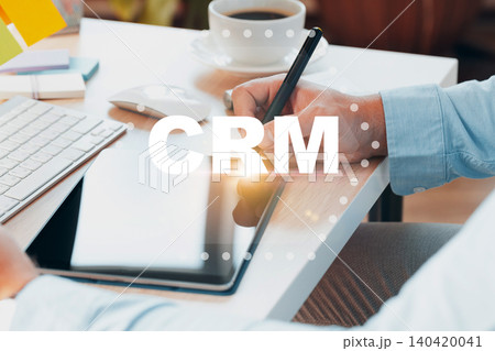 Using a digital tablet for CRM tasks at a work desk with a coffee cup nearby Using a digital tablet for CRM tasks at a work desk with a coffee cup nearby 140420041