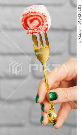 Dessert on a fork held by a hand with green nails in a casual indoor setting 140420105
