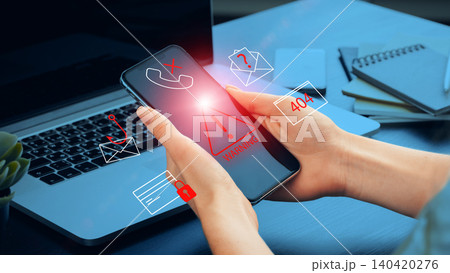 Scam call warning message on a mobile phone near a laptop and office items 140420276
