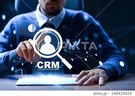 Professional using CRM software on a tablet in a dark office setting 140420428