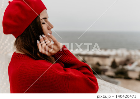 Woman beret sea posing in a red sweater against an ocean background with eyes closed reflecting a peaceful and calm mood Woman beret sea posing in a red sweater against an ocean background with eyes closed reflecting a peaceful and calm mood 140420473