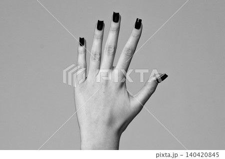 Hand with black nail polish shows fingers in close view against a plain background Hand with black nail polish shows fingers in close view against a plain background 140420845