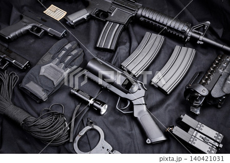 Collection of firearms and tactical gear on a black background at a gun enthusiast event Collection of firearms and tactical gear on a black background at a gun enthusiast event 140421031
