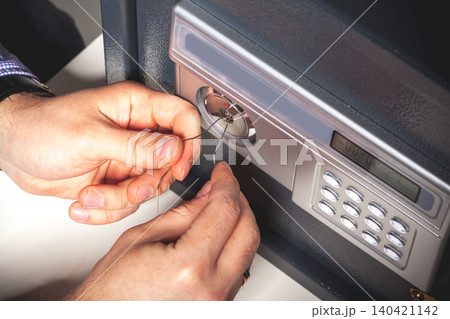 Person opens a safe using a pick tool and wire at a workspace during the day Person opens a safe using a pick tool and wire at a workspace during the day 140421142