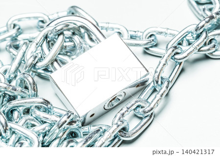Metal lock and chain placed on a white surface showcasing security and protection measures 140421317