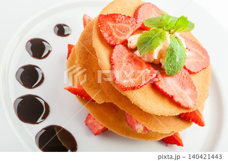 Delicious dessert with layers of sponge, strawberries, cream, and chocolate sauce on the plate Delicious dessert with layers of sponge, strawberries, cream, and chocolate sauce on the plate 140421443