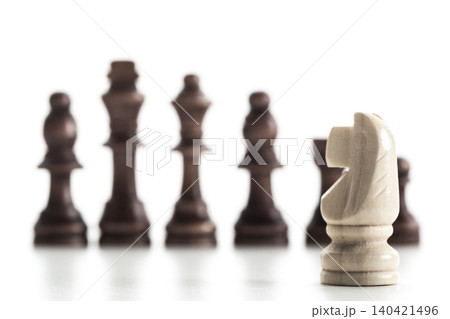 Chess pieces on a board with a knight in focus during a game in a indoor setting Chess pieces on a board with a knight in focus during a game in a indoor setting 140421496
