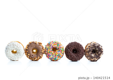 Different types of donuts on display with various toppings arranged in a row Different types of donuts on display with various toppings arranged in a row 140421514