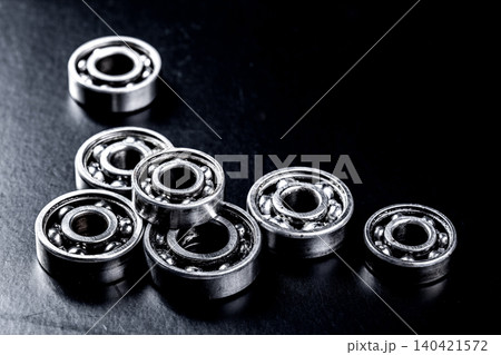 Collection of metal ball bearings on a dark surface in a workshop setting 140421572